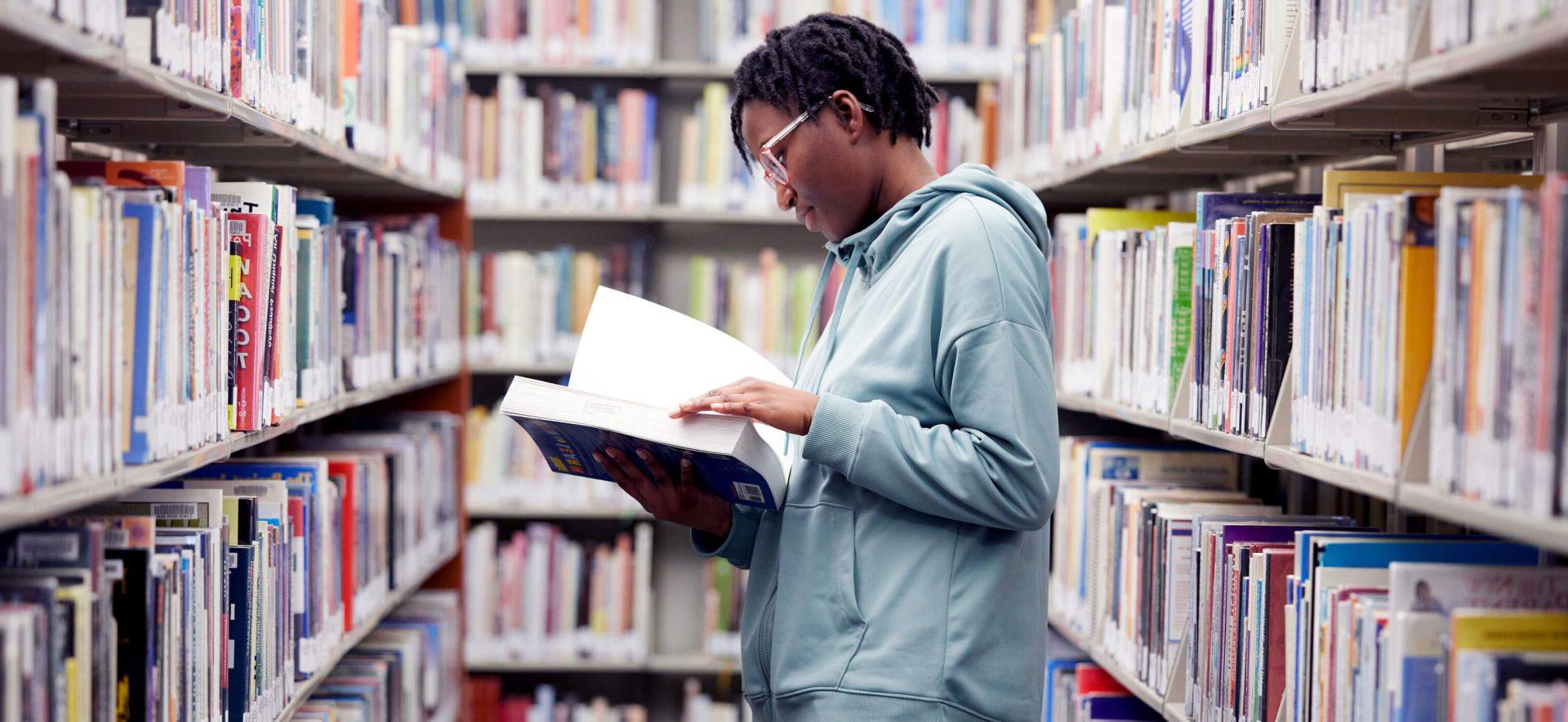 A student in the library looking at a book.